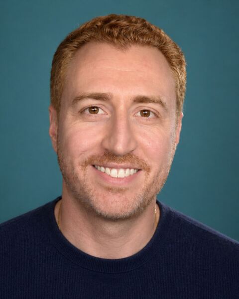 Jason Martin, smiling, in front of a teal background
